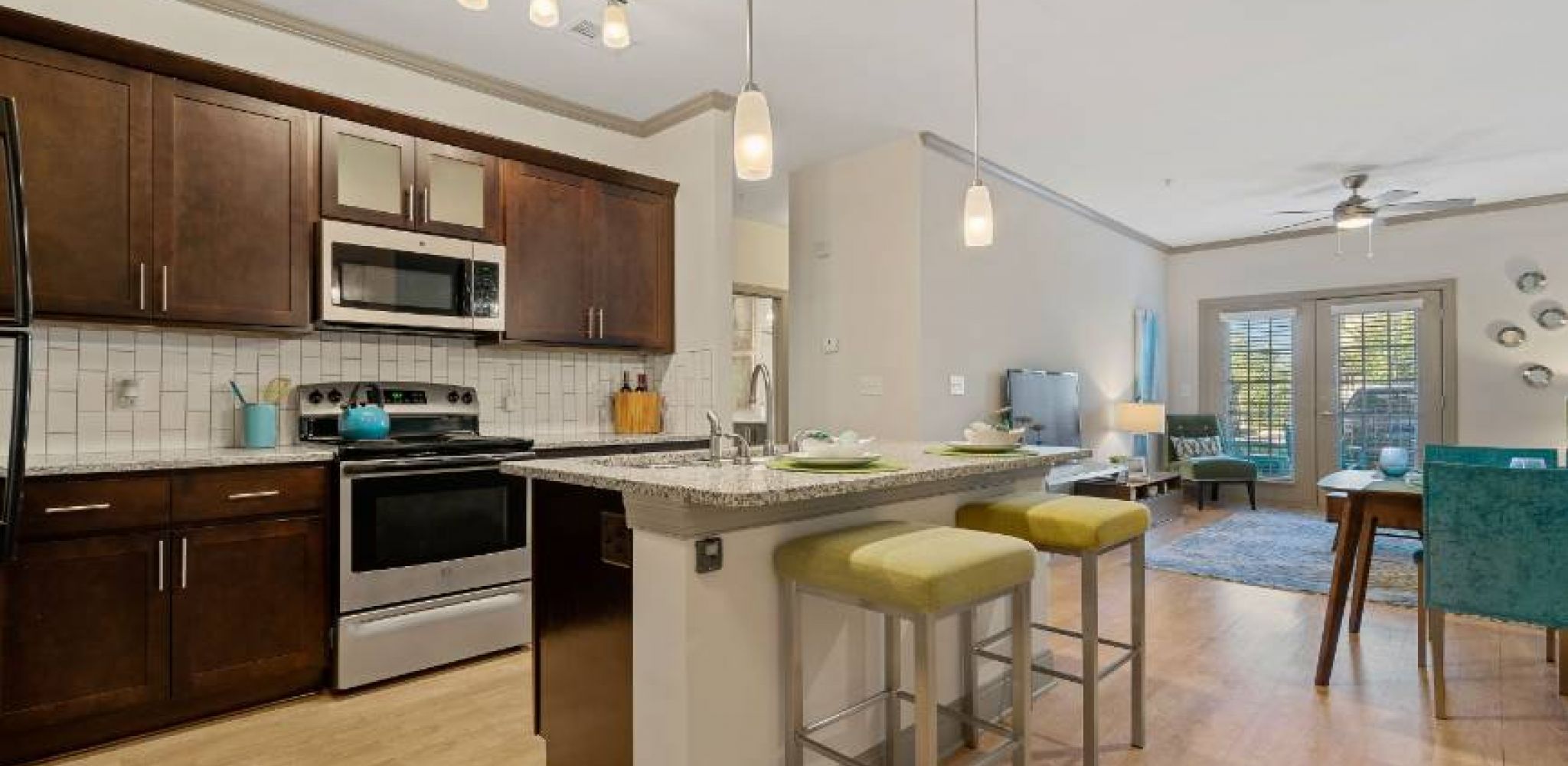 Hawthorne at Southside apartment kitchen with espresso cabinetry, stainless steel appliances, and kitchen island with 2 chairs